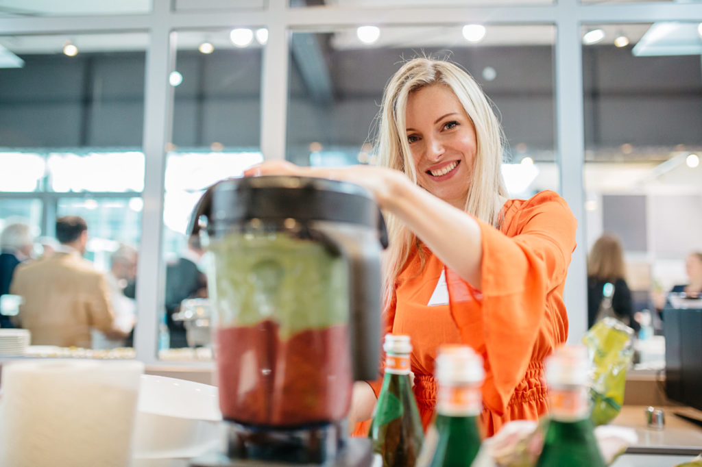Frau orange Jacke Messestand Getränke