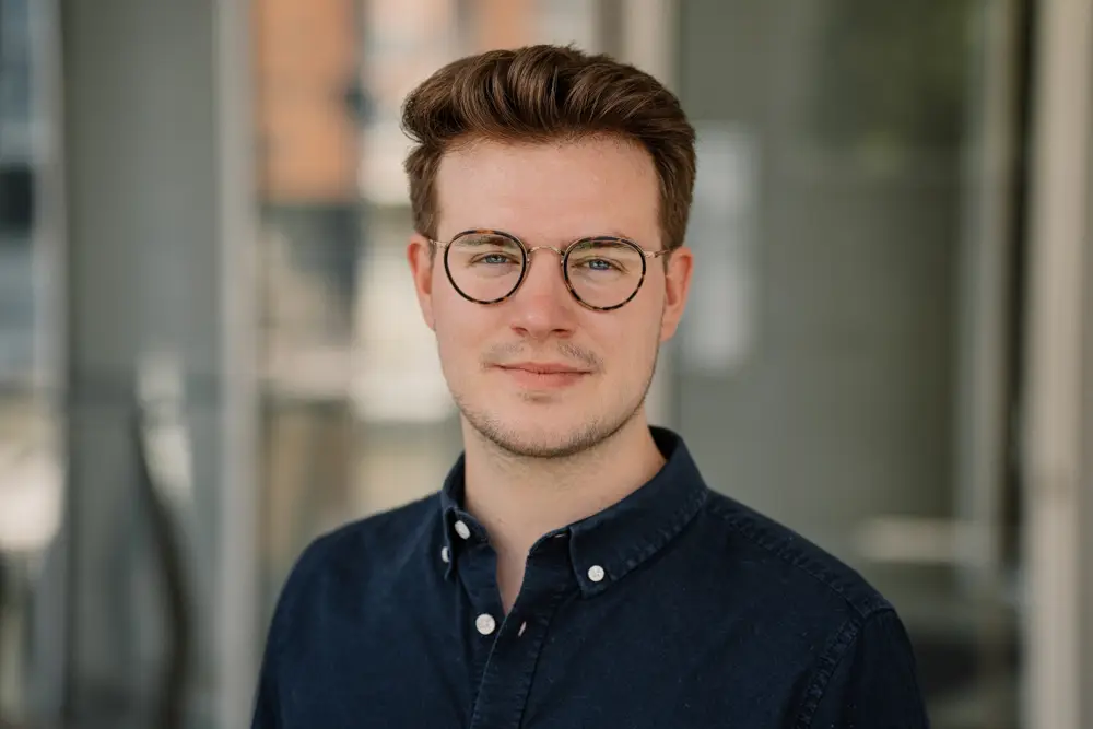 Businessportrait junger Mann Brille dunkles Hemd
